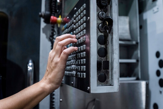 Hand of maintenance engineer operating CNC machine in modern factory