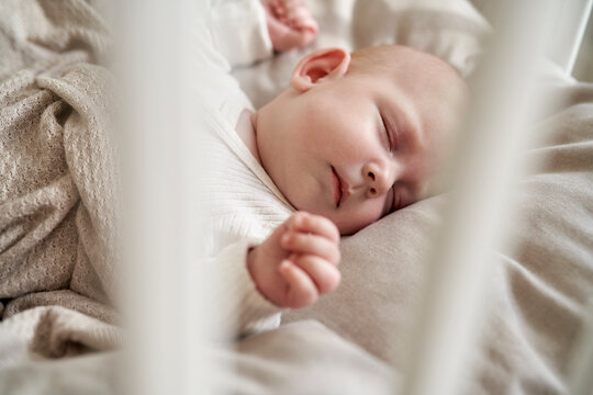 Baby girl with eyes closed sleeping in crib