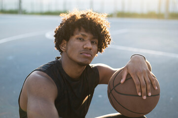 Athlete with curly hair holding basketball at court