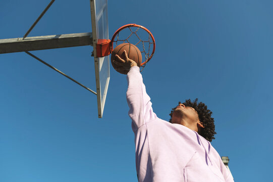 Athlete catching basketball under hoop at sports court