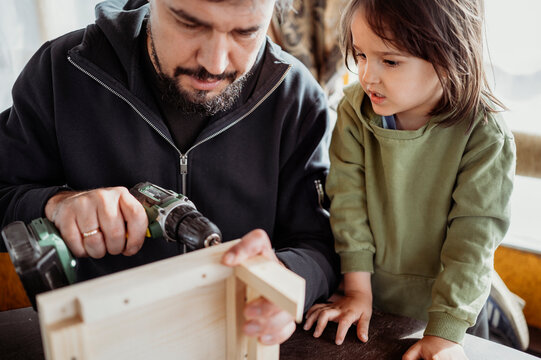 Boy with father building up birdhouse at home