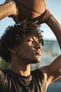 Athlete holding basketball overhead at sunset