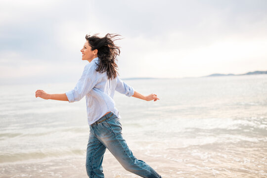 Mature carefree woman running near sea at beach