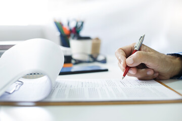 Asian businessman reviewing document reports at office workplace with computer laptop. legal expert, professional lawyer reading and checking financial documents or insurance contract before sign