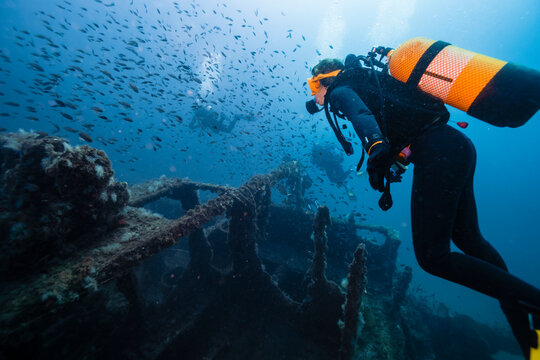 Men and woman scuba diving and examining sunken ship El Naranjito undersea