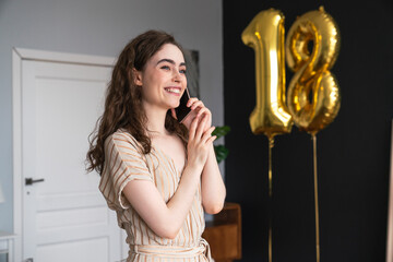 Smiling young woman talking on phone celebrating birthday at home