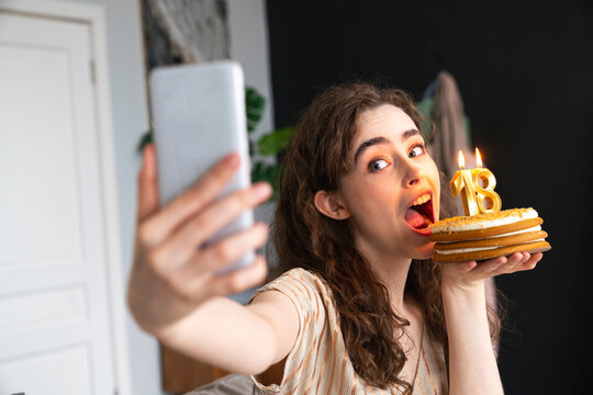 Playful young woman taking selfie with birthday cake