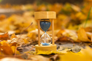 hourglass in fallen autumn leaves.