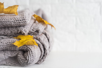 Yellow and Ultimate Gray. Crop of stack gray woolen knitted blankets, warm plaids decorated maple leaf, autumn cozy concept