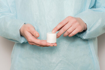 Fototapeta na wymiar Hand of doctor holding jar of ointment, pills, tablets. Medicine bottle mockup