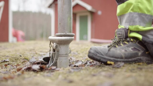 Worker inserting effluent pump nozzle into coupler of septic tank. Low close-up