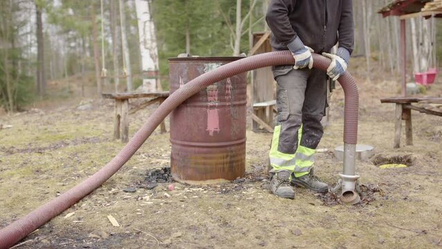 Sanitation worker uses suction hose to pump wastewater out of septic tank