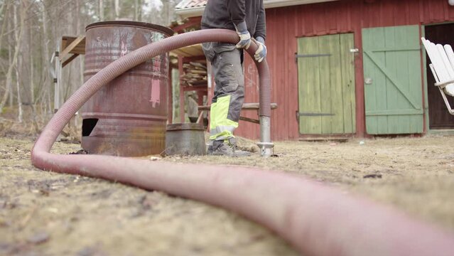 Sanitation worker holds on to suction hose used to empty septic tank