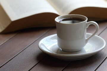 Cup of coffee on the table. Reading a book concept. 