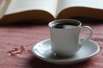 Cup of coffee on the table. Reading a book concept. 