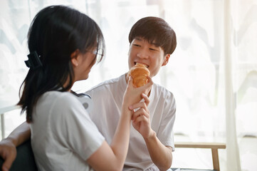 A cute girlfriend feeds a croissant to her boyfriend. love and relationship concepts