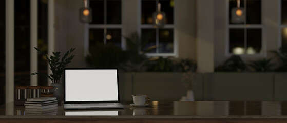 A laptop white screen mockup on a tabletop in modern comfortable room at night.