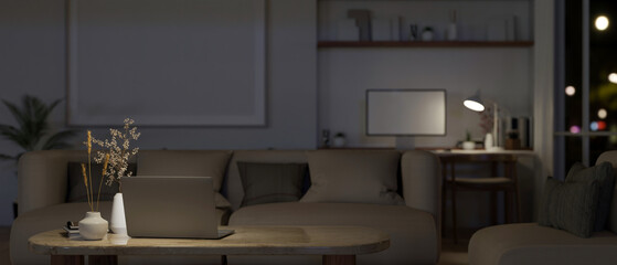 A laptop on a coffee table in cozy minimalist living room at night.