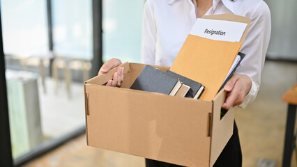 Cropped image of a female office worker holding a cardboard box with her resignation letter.