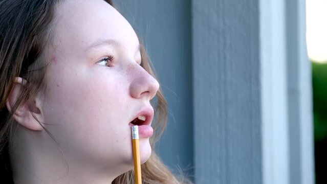 adolescence think dream miss close-up face of teenage girl taking pencil in mouth to think thinking street girl young woman draws does homework