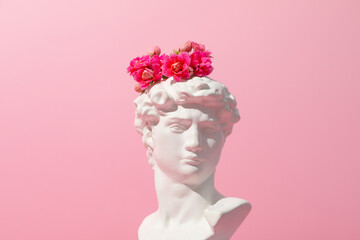 Ancient head with flowers on pink background