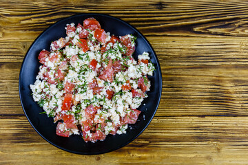Salad with tomatoes, cottage cheese, dill and olive oil on a wooden table. Top view
