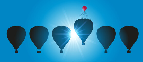 Concept de l’ingéniosité et de la réussite avec des montgolfières dans le ciel, dont une, vole plus haut grâce à un ballon de baudruche.