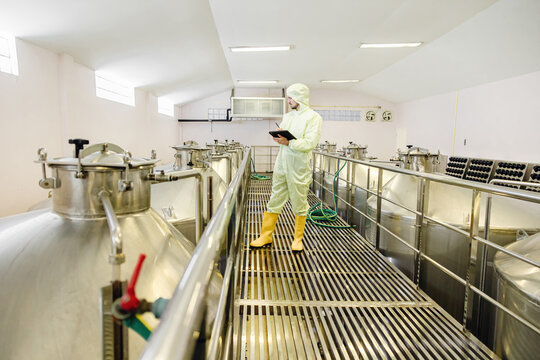 Brewery beverage factory worker working check fermentation tank with clean and hygiene cover suit. - Powered by Adobe
