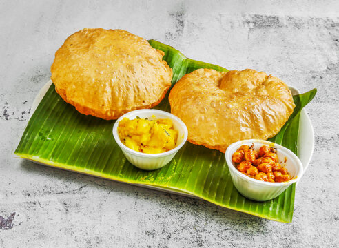 poori set or puri with chnnay and veg curry with chutney, raita and sauce served in dish isolated on banana leaf top view of indian and singapore spicy food