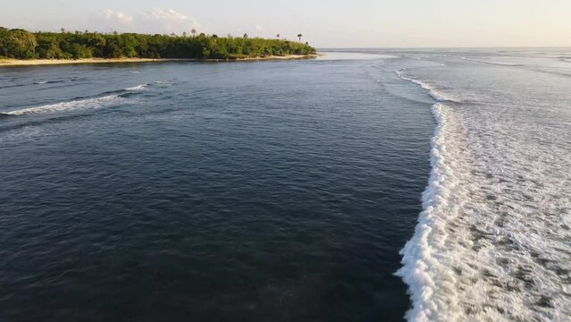 Flying over foamy ocean waves at the coastline of a tropical island, G-Land, Grajagan Bay, Plengkung Beach, Java, Indonesia
