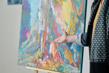Close-up of artist pointing at picture and presenting his artwork at exhibition