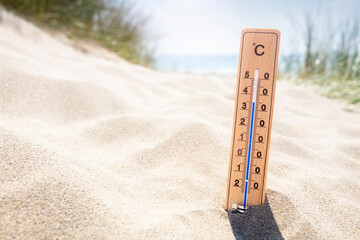 Thermometer in sand on the beach showing high temperature background