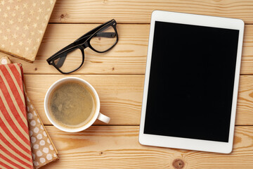 Top view of wooden table with white digital tablet with black screen on it