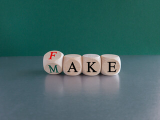 Fake it until you make it symbol. Turned a wooden cube and changes red word Fake to Make. Beautiful green background. Business, and fake it till you make it concept. Copy space.