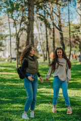 Fototapeta premium Two lovely careless girls hanging out in the park on a beautiful sunny day. They are having fun conversation and smiling