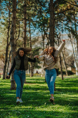 Naklejka na ściany i meble Two happy, smiley, gorgeous girls, dancing while walking in the park