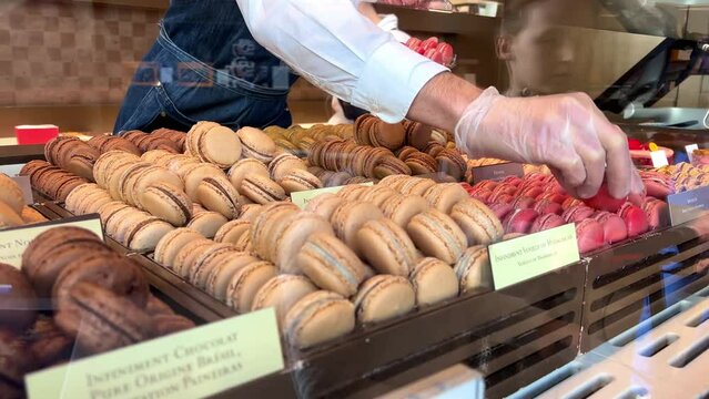 Life in the Confectionery Makarunov Pierre Edme in white sellers fuss trying to please buyersA lot of macaroons and a girl in white chooses a taste 06.04.22 Paris France. High quality 4k footage