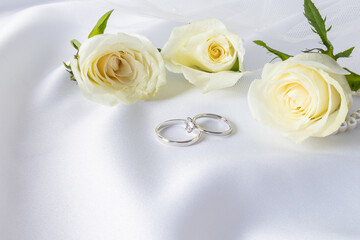 Wedding arrangement with two wedding rings made of platinum with diamonds and delicate tea roses on...