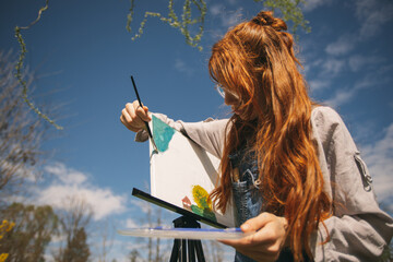 Girl painting on a easel at the park