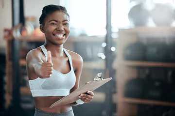 Fotobehang Persoonlijk Thumbs up, personal trainer portrait or happy black woman at gym for workout, exercise or fitness training. Healthy sports girl, thumb up or proud coach smiling with yes hand sign, like or clipboard  © Beaunitta Van Wyk/peopleimages.com