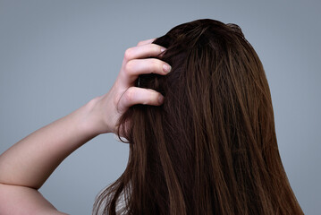 A young woman with dirty greasy hair on a gray background. - obrazy, fototapety, plakaty