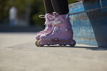Skater girl wearing modern aggressive in-line skates in a skatepark. Young female skating on roller...