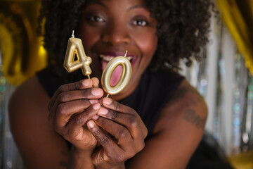 African woman smiling in her 40 birthday party with 40 birthday golden candles.