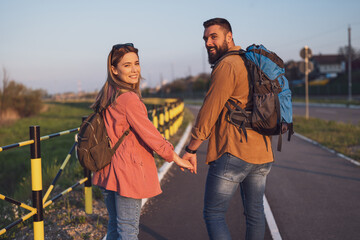 Happy adult couple is walking together by the road and holding hands.