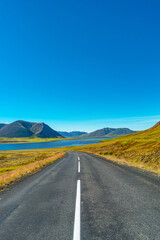 Cover page with a paved road and Icelandic colorful and wild landscape with fjords and sea at summer time, West Iceland