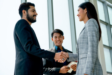 Asian business man and woman shake hands together in front of business man with smiling show success of cooperation together in the project of company with day light.