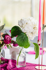 Decor details closeup. Decoration with pink, flowers roses, hydrangea, candles for birthday party, wedding reception. Luxury elegant setting dinner in restaurant. Organized event, served banquet