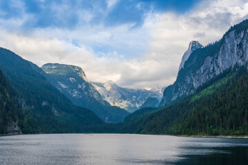 Fototapeta na wymiar Beautiful landscape mountain forest lake view. Amazing summer cloudy scenery of Gosausee mountain lake and Dachstein mountain summit. Colorful scenery in Alps. Popular travel and hiking destination.