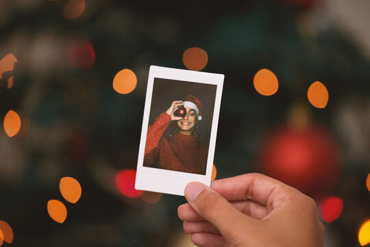 Hand, christmas and picture with a person looking at a photograph of a memory on a blurred background. Home, nostalgia and holidays with an adult holding a photo to remember past memories on xmas eve