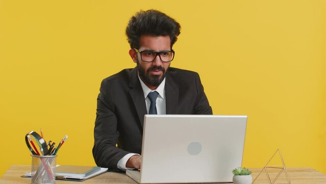 Indian businessman programmer software developer working on laptop loses becoming surprised by bad news results, fortune loss fail, computer virus at office. Deadline, bankruptcy. Freelancer young man